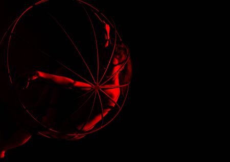 silhouette of sexy female dancer in red light on a dark background. leggy woman in a bodysuit with metal rings. night club concepteの写真素材