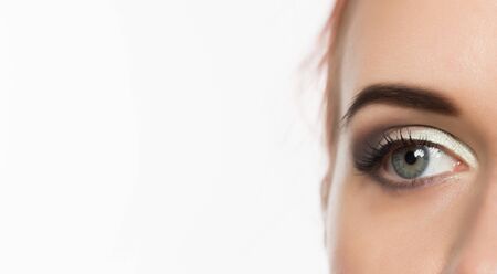 Close-up grey eye with professional makeup looking at the side, on a white background. free space for textの写真素材