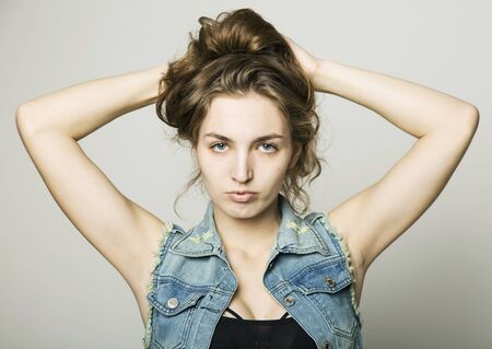 young beautiful happy stylish hipster girl in a denim jacket and shorts posing on a light backgroundの写真素材