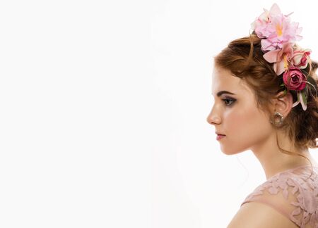 portrait of cute young woman in delicate pink dress, professional hairstyle with wreath. free space for your textの写真素材