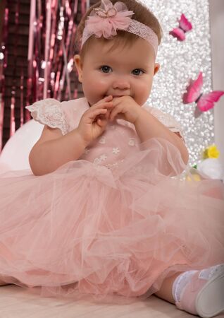 beautiful fashionable little baby in pink dress. little princess poses like a dollの写真素材