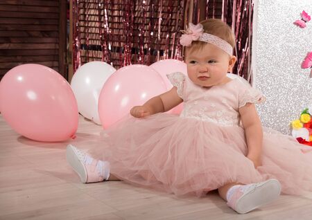 beautiful fashionable little baby in pink dress. little princess poses like a dollの写真素材