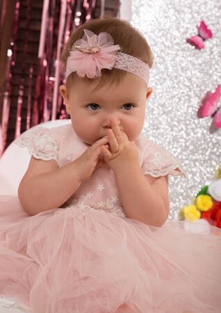 beautiful fashionable little baby in pink dress. little princess poses like a dollの写真素材
