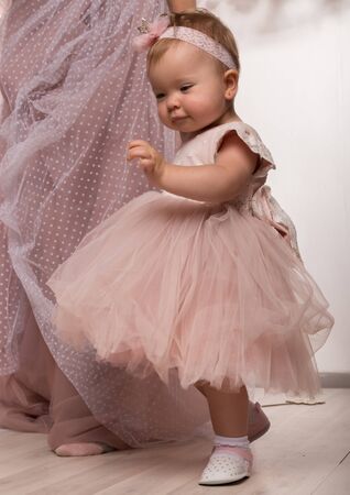 beautiful fashionable little baby in pink dress. little princess poses like a dollの写真素材