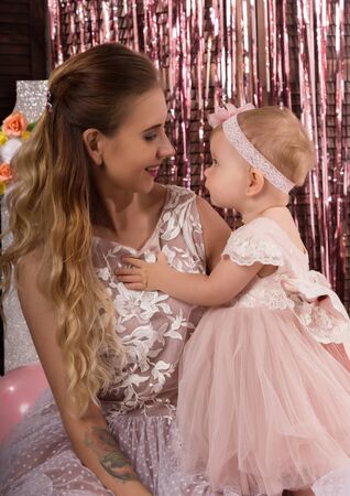 beautiful fashionable little baby in pink dress. little princess poses like a doll with her mamの写真素材