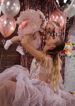 beautiful fashionable little baby in pink dress. little princess poses like a doll with her mamの写真素材