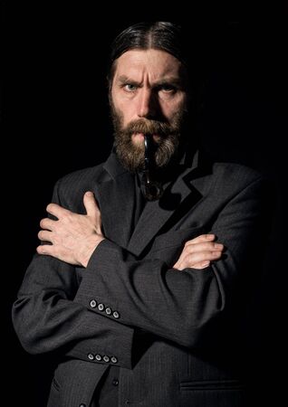 vintage handsome bearded man with a smoking pipe on a dark backgroundの写真素材