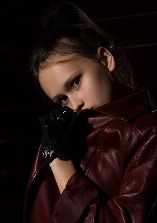 Beautyful Girl in leather jacket in a dark. Mysterious disobedient child, problems with early growing girlsの写真素材