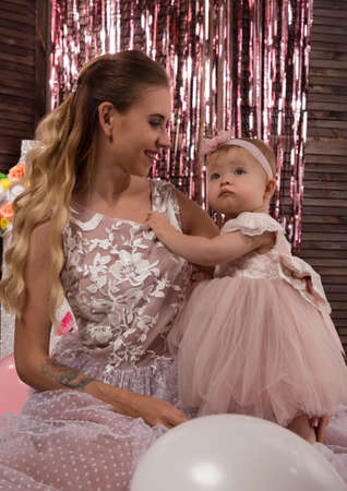 beautiful fashionable little baby in pink dress. little princess poses like a doll with her mamの写真素材
