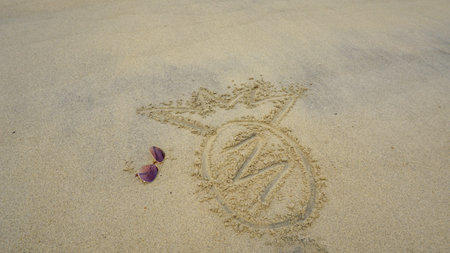 Drawing pineapple on the sand at the beach, natural background. written in sand. White sand beach with pineapple and sunglasses, vacation for backgroundの写真素材