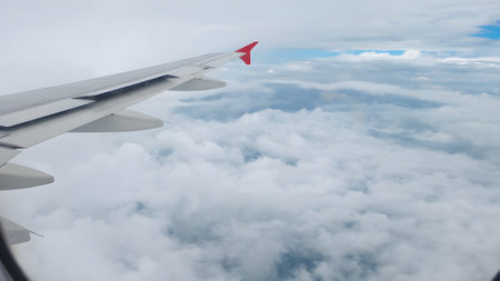Aerial view from a flying plane in the sky over the clouds. Photographs of the sky taken from an airplane. Image of airplane wing flying above the clouds. The clouds are soft and clean like cotton candy.の写真素材