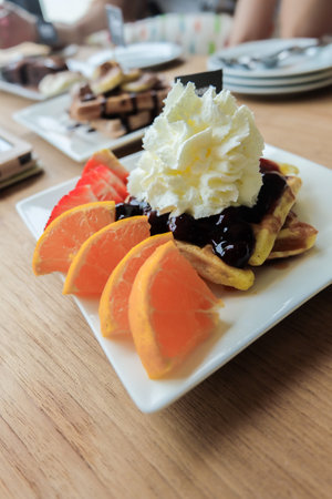 Plate with yummy waffles, whipped cream, berries jams and orange. Fruit Parfait Breakfast. High...