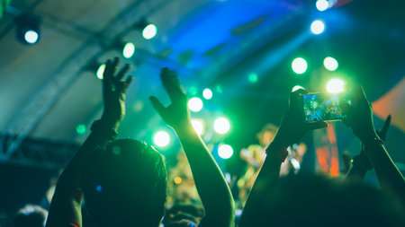 Vibrant light bokeh in background. Party, Event, Celebration. Out of focus concert spot lights as background. Mobile phone camera take pictures in Concert. Silhouettes of people with concert stage lights.の写真素材
