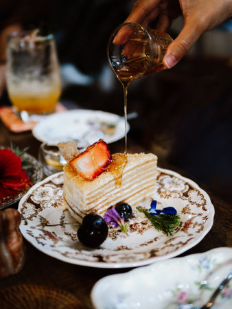 Crepe cake bakery piece with strawberry and honey sauce on wood table. Close up a piece of strawberry crepe cake on a white plate with strawberry fruits on a wooden table background.の写真素材