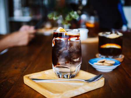 Iced Americano Coconut. A clear glass of layer iced americano with young fresh coconut water and coconut meat on table, a summer cold drink and home barista concept.の写真素材