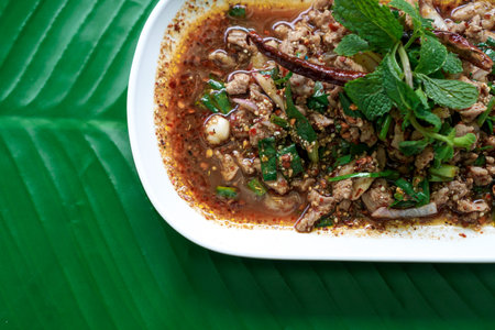 Spicy duck minced salad on banana leaf. Thai local food recipe Lab Ped. Larb Ped, Laab Ped, Thai food, spicy minced duck salad served with chilli, slice fragrant and mint leavesの写真素材