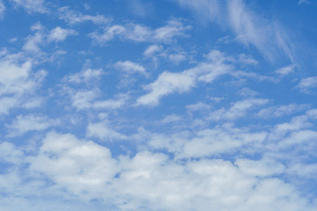 Blue sky background with tiny clouds. Nature abstract background for your design. Beautiful wispy clouds against blue skyの写真素材