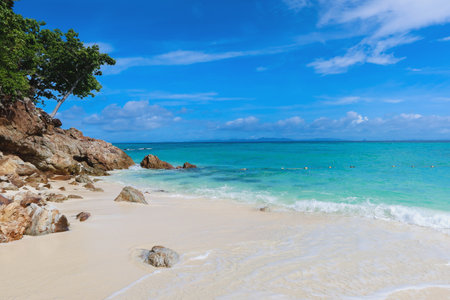 A calm beach with clear water, gentle waves, and a sunny sky with clouds. Clear tropical water and cumulus clouds on the horizon, Thailand. Ocean Beach with blue sky on a sunny day at the summer sea.の写真素材