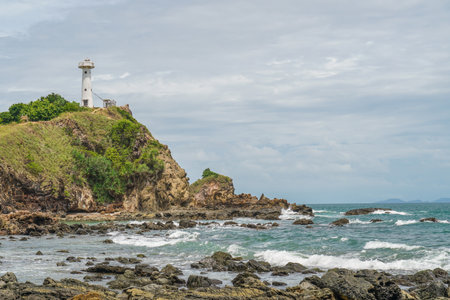 Scenic view of a lighthouse on a cliff, on a sunny day. White lighthouse and green forest and bright sky. At the Mu Koh Lanta National Park, Thailand.の写真素材