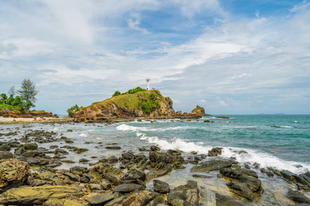Scenic view of a lighthouse on a cliff, on a sunny day. White lighthouse and green forest and bright sky. At the Mu Koh Lanta National Park, Thailand.の写真素材