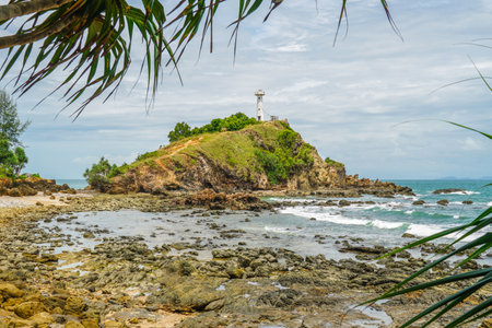 Scenic view of a lighthouse on a cliff, on a sunny day. White lighthouse and green forest and bright sky. At the Mu Koh Lanta National Park, Thailand.の写真素材