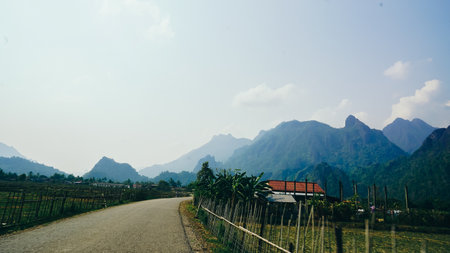 Dirt road in farm with limestone mountains in background, Vang Vieng, Laos. A view over rice fields...