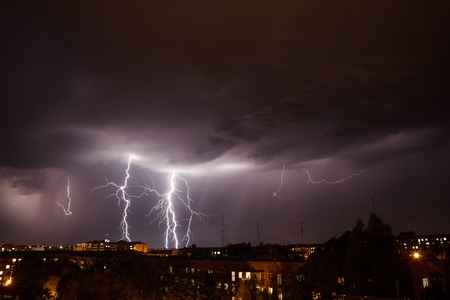Lightning storm over city in purple lightの写真素材