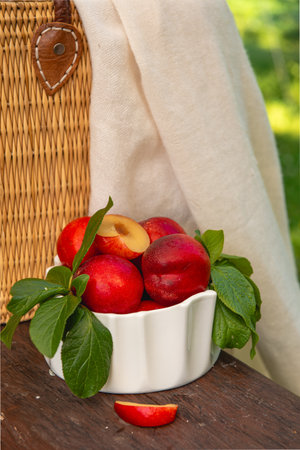 Ripe juicy nectarines in a white bowl on a wooden tableの写真素材