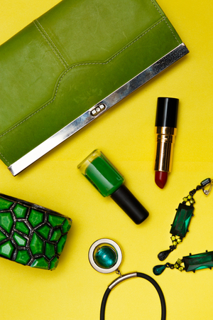 Top view of female fashion accessories . Green handbag with sunglasses, gold watch , lipstick , perfume , rings , smart phoneの写真素材