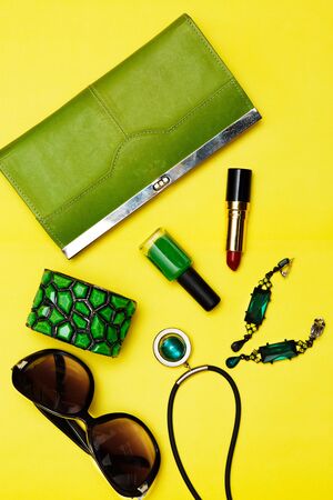 Top view of female fashion accessories . Green handbag with sunglasses, gold watch , lipstick , perfume , rings , smart phoneの写真素材