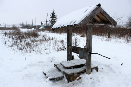 Rural landscape with a view of the street in a village in the winter and well with drinking water.の写真素材
