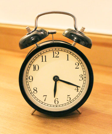 Classic black metal alarm clock with white dial on the table