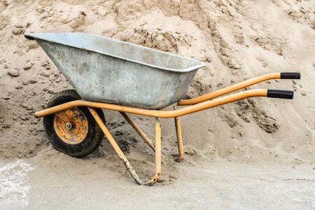 Construction wheelbarrow close-up against a pile of sandの写真素材