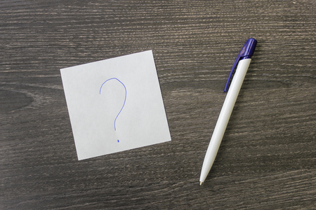 A pen and a leaf with a question mark lie on the office tableの写真素材