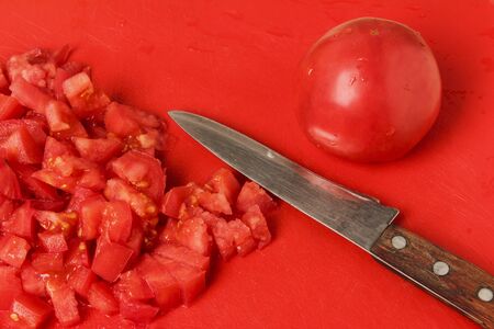 Sliced tomatoes on a red plastic cutting boardの写真素材
