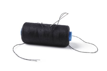Spool with black threads and a sewing needle stuck into it, isolated on a white background
