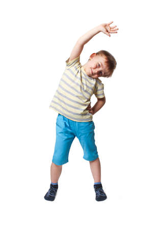 The boy in blue shorts and a yellow striped t-shirt doing body tilts to left and right sidesの写真素材