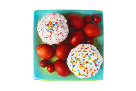 Festive easter cakes and painted eggs on a platter isolated on white background. View from above