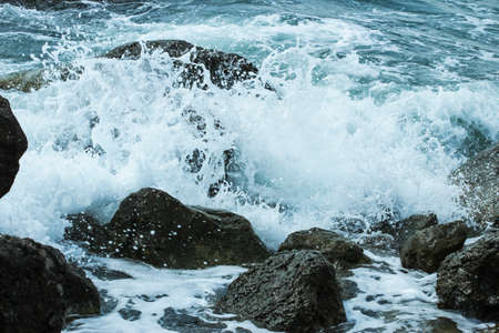Sea waves crash against rocks and sprayの写真素材