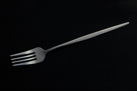 Close-up of metal fork on black tabletop
