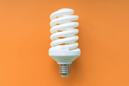 Light bulb on orange background. Fluorescent,  energy savings led lamp.