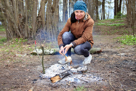 woman outdoors cooks by the fire