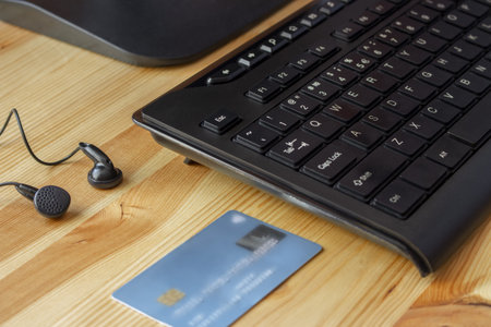 Keyboard, headphones and bank card on wooden background
