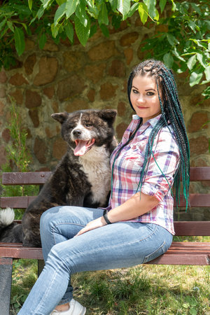 A woman sits on a bench with a dogの写真素材