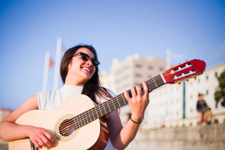 A Young Latin woman take the Sommertime to travel, a vacation opportunity to play guitar on the...