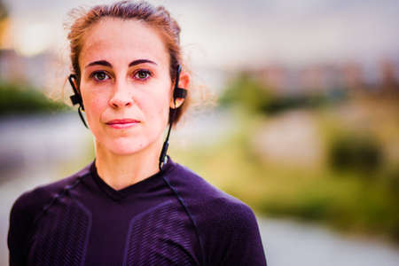 headshot Real running woman training cardio outside for marathon listening music with headphones. Lifestyle portrait in Spain, Street outside sport.の写真素材