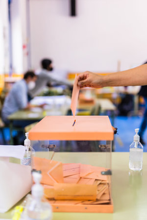 MADRID, MADRID - SPAIN - MAY 05, 2021 - Autonomous community of Madrid elections. Democraty referendum for government vote. Hand posing an envelop in a ballot box for Madrid community electionsのeditorial素材