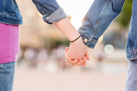Unrecognizable lesbian couple holding hands. Young dating together in a female relationshipの写真素材