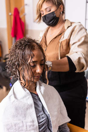 Makeover haircut in beauty salon with Latin hairdresser professional. mixed race with facemaskの写真素材
