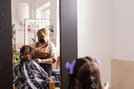 Latin small business Beauty salon. Entrepreneur hairdresser woman and mixed race client. Facemaskの写真素材